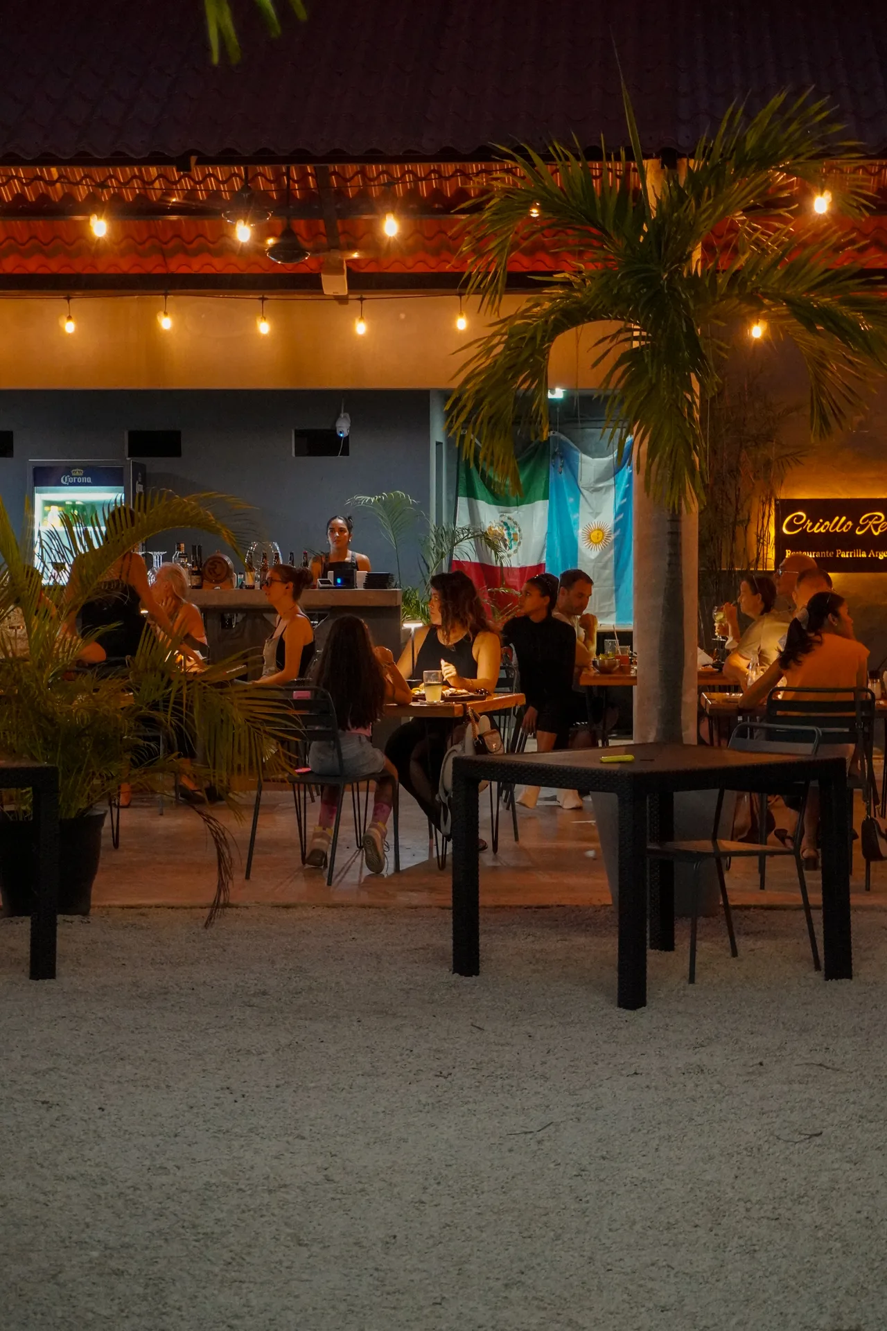 Mesas, plantas y luces del restaurante Criollo Restó
